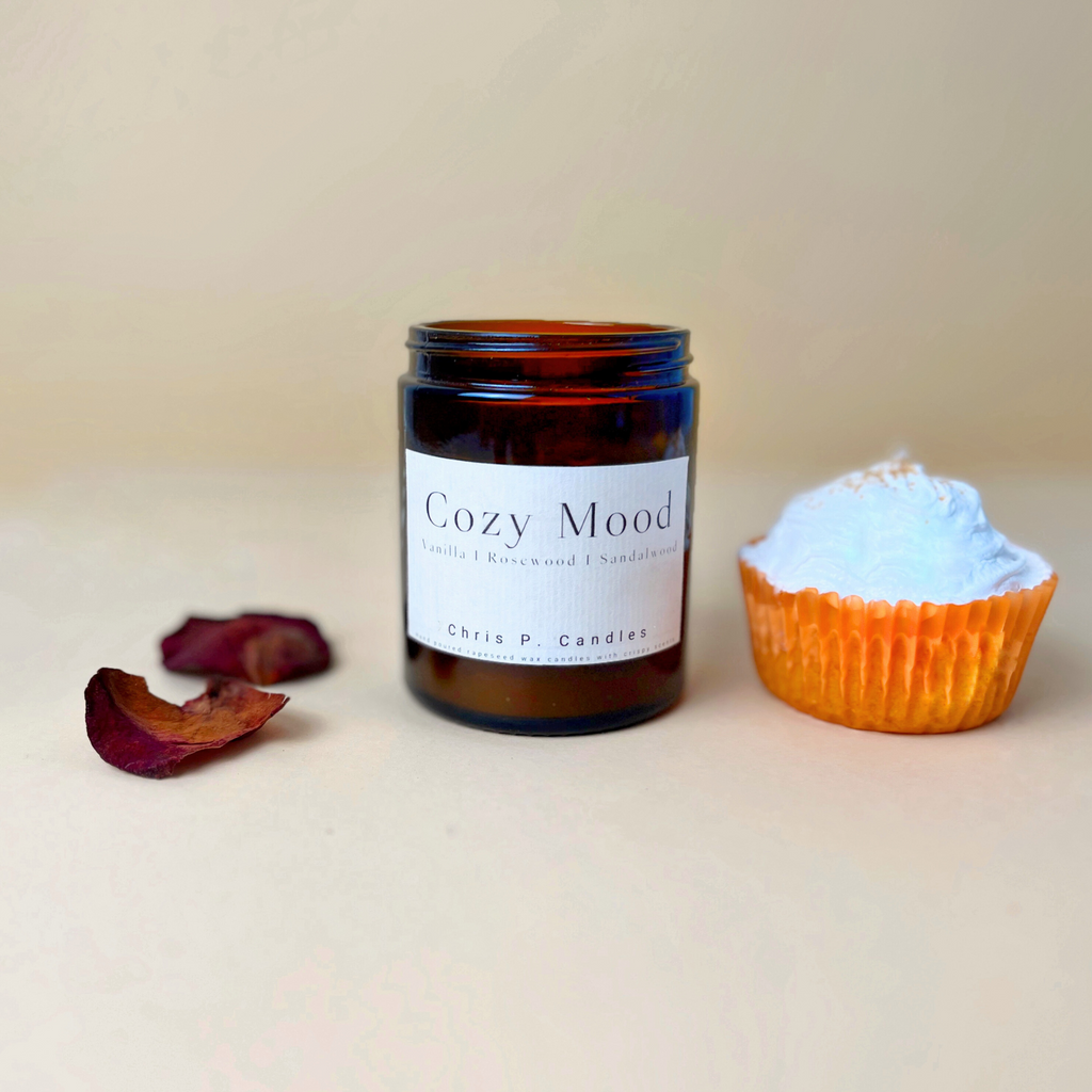 Hochwertige Duftkerze von Chris P. Candles "Cozy Mood" neben Rosenblättern und Vanille-Cupcake vermittelt Wärme und Geborgenheit. Das perfekte Geschenk für die kalten Herbsttage und Weihnachten.