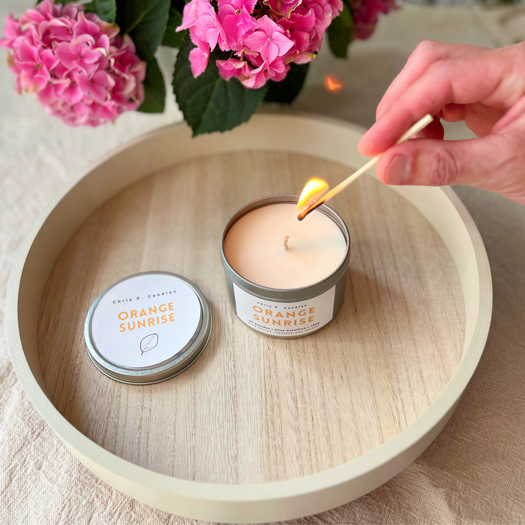 Frisch duftende Orange‑Sunrise-Kerze auf einem hellen Tisch – natürliche, handgegossene Duftkerze, tolle Geschenkidee für besondere Momente.