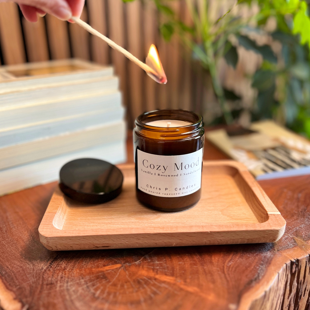 Die Cozy Mood Duftkerze von Chris P. Candles steht auf einem Holztisch und verbreitet mit Vanille, Rosenholz und Sandelholz eine warme, gemütliche Atmosphäre.